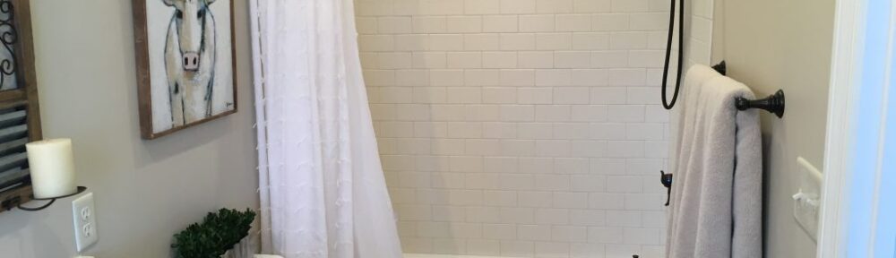 Bathroom with tiled shower and decorative artwork.